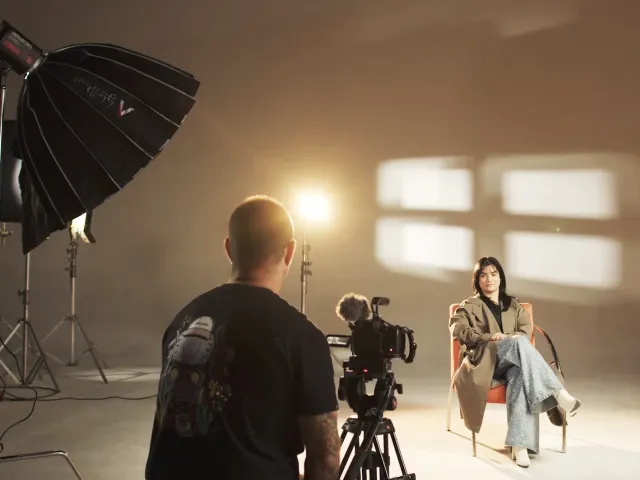 Bastidores de gravação: câmera em tripé filmando uma entrevista em estúdio